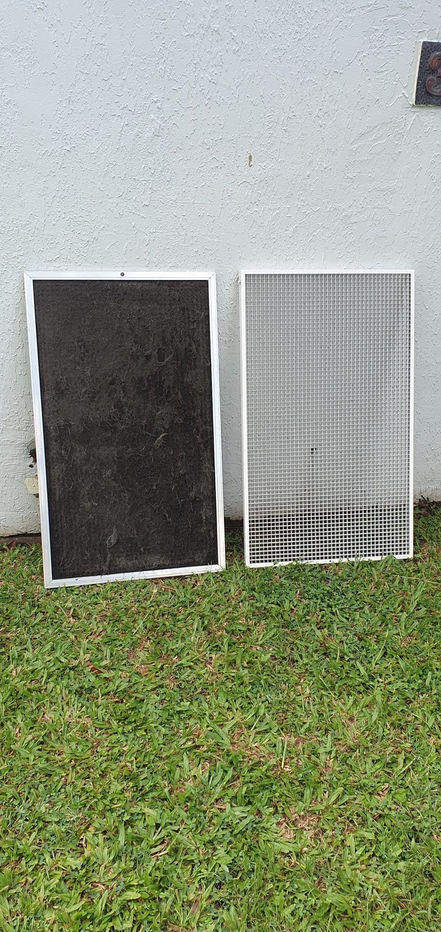 A dusty ducted return air filter beside the return air grille, both removed for cleaning on a Natural Breeze job